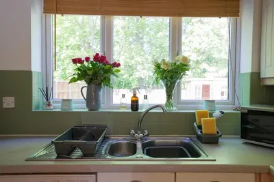 a kitchen sink with vases of flowers in a window at Spacious 5 Bedrooms Sleeps 9 3 Bath and Parking Ideal for Contractors in Chesfield