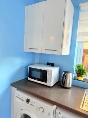 a kitchen with a microwave and a washing machine at Heartfelt Cambridge Home in Cottenham