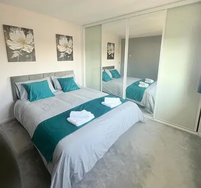 a bedroom with a large bed with towels on it at Heartfelt Cambridge Home in Cottenham