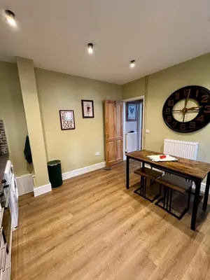 a living room with a table and a clock on the wall at Quaint Bury St Edmunds Cottage in Bury Saint Edmunds