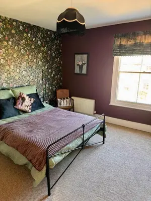 a bedroom with a bed with a floral wall at Quaint Bury St Edmunds Cottage in Bury Saint Edmunds