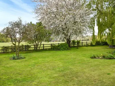a fence in a field with trees and grass at Swallowdale in Flordon