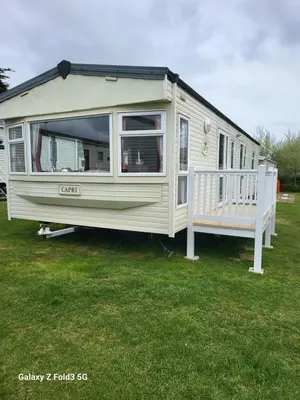 a white caravan parked in a yard with a porch at Home from home in Holland-on-Sea