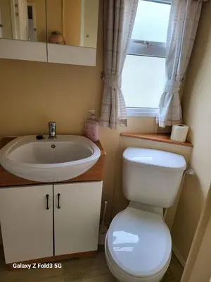 a bathroom with a toilet and a sink and a window at Home from home in Holland-on-Sea