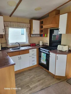 a kitchen with white cabinets and a stove top oven at Home from home in Holland-on-Sea