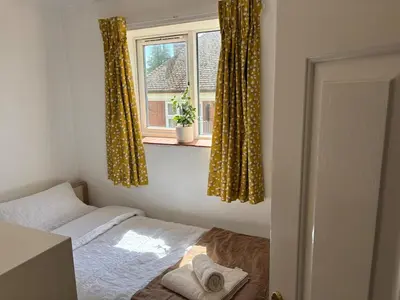 a bedroom with a bed and a window with curtains at Next to double Nobel Laureate in Trumpington