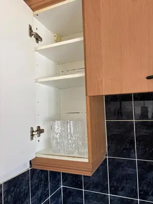 a cupboard in a kitchen with black tiles at Next to double Nobel Laureate in Trumpington