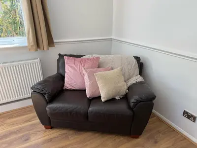 a black leather couch with pillows on it in a room at Stansted Stop Over in Takeley