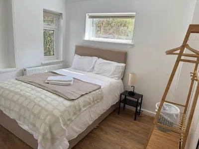 a bedroom with a bed with white sheets and two windows at Stansted Stop Over in Takeley