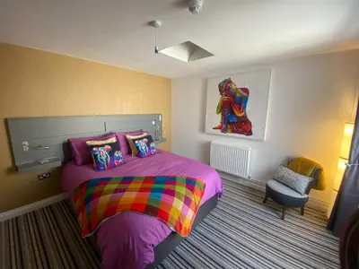 a bedroom with a purple bed and a chair at Sanctuary Rooms in Brightlingsea