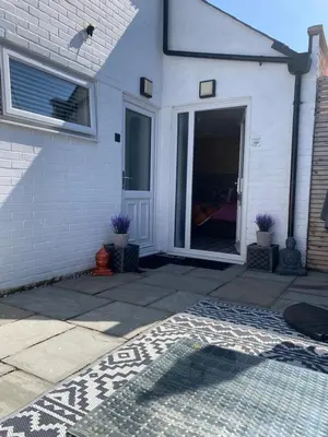 a white house with a door and a patio at Sanctuary Rooms in Brightlingsea