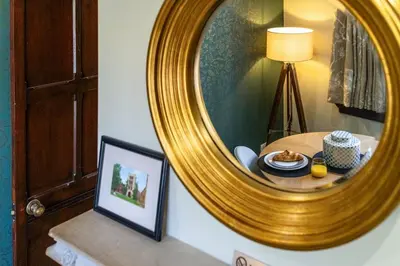 a mirror on a wall with a table with a plate of food at Tower Cottage - Medieval Grid Townhouse in Bury Saint Edmunds