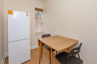 a kitchen with a wooden table and a refrigerator at Spacious 3 bed flat in Colchester - Free parking in Hythe
