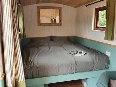 a small bed in a small room with a mirror at Delightful shepherd's hut in a rural location in North Fambridge