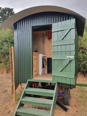 a green shed with a door and a stove at Delightful shepherd's hut in a rural location in North Fambridge