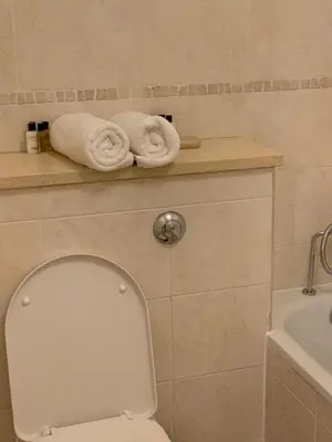 a bathroom with a toilet and towels on a shelf at Two Bed Flat By The Beach No Parties No Events in Southend-on-Sea