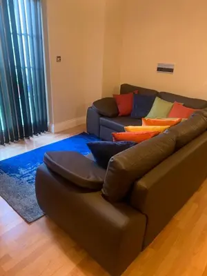 a living room with a brown couch with colorful pillows at Two Bed Flat By The Beach No Parties No Events in Southend-on-Sea