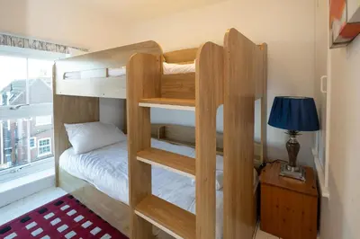 a bedroom with bunk beds with a lamp and a bed at 7 Coastguards Cottages - Aldeburgh Coastal Cottages in Aldeburgh