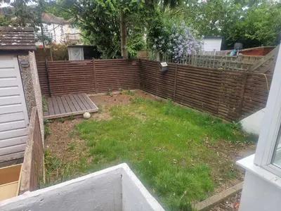 a backyard with a wooden fence and a bench at Arundel Road, RM30RX in Harold Wood