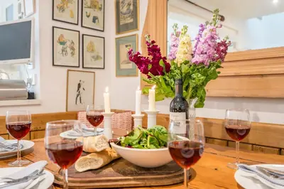 a table with wine glasses and a bowl of salad and flowers at 207 High Street, Aldeburgh in Aldeburgh