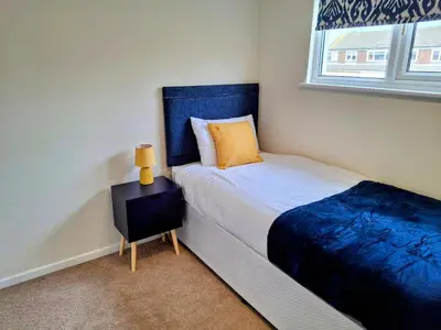 a bedroom with a bed with a blue headboard at Modern townhouse with easy access to London in Ingatestone