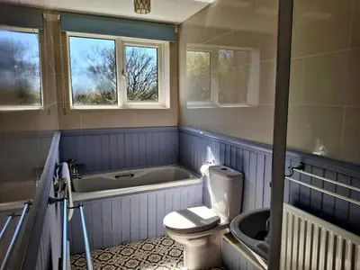 a bathroom with a tub and a toilet and a sink at Modern townhouse with easy access to London in Ingatestone