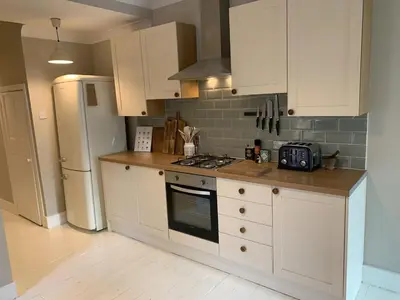 a kitchen with white cabinets and a stove and refrigerator at Homely flat just off Leigh Broadway in Southend-on-Sea