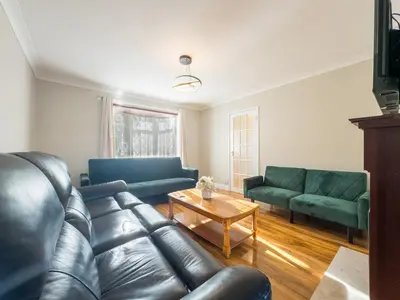 a living room with a leather couch and a table at Urban Ease Basildon in Basildon