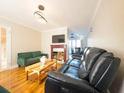 a living room with a black leather couch and a table at Urban Ease Basildon in Basildon