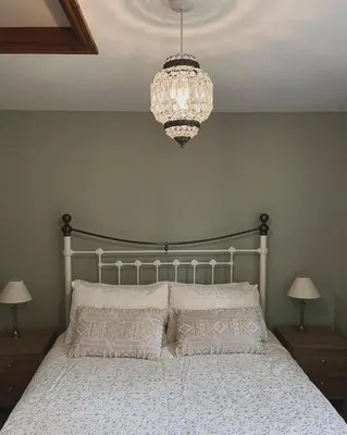 a bedroom with a bed with a chandelier above it at Elm Barn in Diss