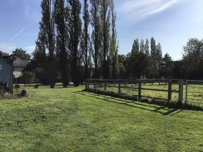 a fence in a field with trees and grass at Elm Barn in Diss