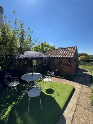 a table and chairs and an umbrella in a yard at 5 chapel lane Wymondham Norfolk in Wymondham