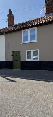 a house with a green door and two windows at 5 chapel lane Wymondham Norfolk in Wymondham