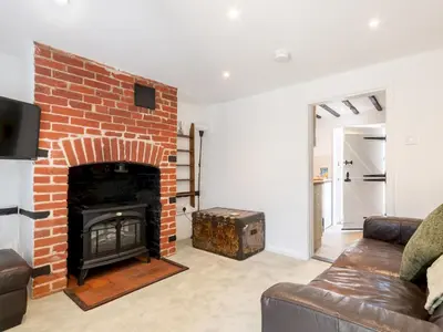 a living room with a brick fireplace and a couch at Magnolia Cottage your cosy Getaway Pass the Keys in Chelmsford