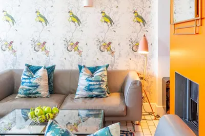 a living room with a couch with a bird wallpaper at Edinburgh House 4 in Aldeburgh
