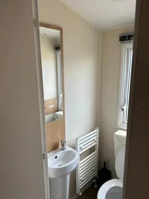 a bathroom with a sink and a toilet and a mirror at Perfect days away - 3 bedroom 1 shower with decking & bedding in Colchester