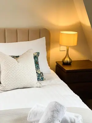 a bed with a pillow and a lamp on a table at Very best location - Luxury boutique apartment by river and historic city centre in Cambridge