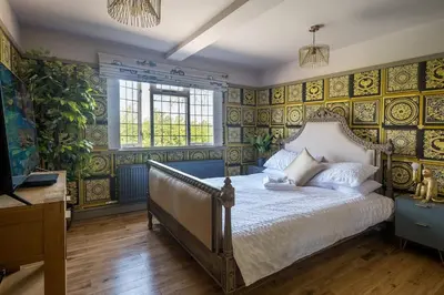 a bedroom with a bed with yellow and blue wallpaper at Huge 8 Bed Manor House with Hot Tub, Cinema Room, Games Room in Hailsham