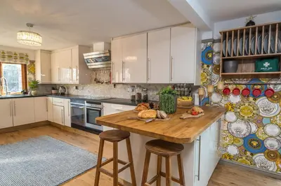 a kitchen with white cabinets and a wooden table at Huge 8 Bed Manor House with Hot Tub, Cinema Room, Games Room in Hailsham