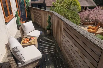 a balcony with two chairs and a tray of fruit on a table at Huge 8 Bed Manor House with Hot Tub, Cinema Room, Games Room in Hailsham
