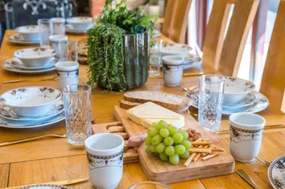a wooden table with cheese and grapes on a plate at Huge 8 Bed Manor House with Hot Tub, Cinema Room, Games Room in Hailsham