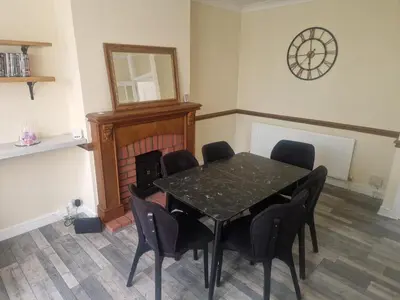 a dining room with a table and chairs and a clock at 1930s conversion two apartment in Harold Wood