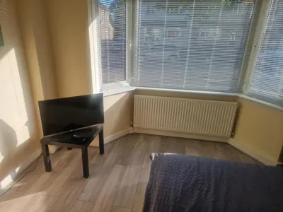 a room with a chair in front of a window at 1930s conversion two apartment in Harold Wood