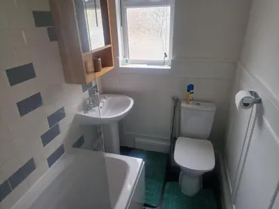 a small bathroom with a toilet and a sink at 1930s conversion two apartment in Harold Wood