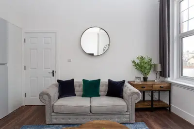a living room with a couch and a mirror at 1 Bed Apartments, 2 Mins to Beach, Sleeps 4 in Southend-on-Sea