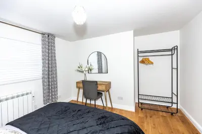 a bedroom with a bed and a desk and a mirror at First Class Flat in Brandon