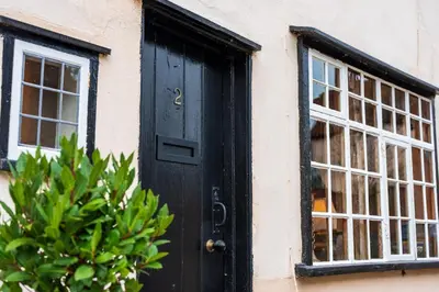 a black door and a window on a building at Cosy & charming medieval 'Bumble Cottage' in Kersey