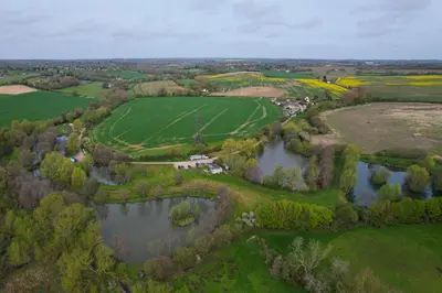 an aerial view of a farm and a lake at Cosy & charming medieval 'Bumble Cottage' in Kersey