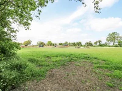 a field of grass with trees and buildings in the background at Woodpecker in Cambridge