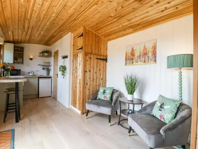 a living room with two chairs and a kitchen at Woodpecker in Cambridge